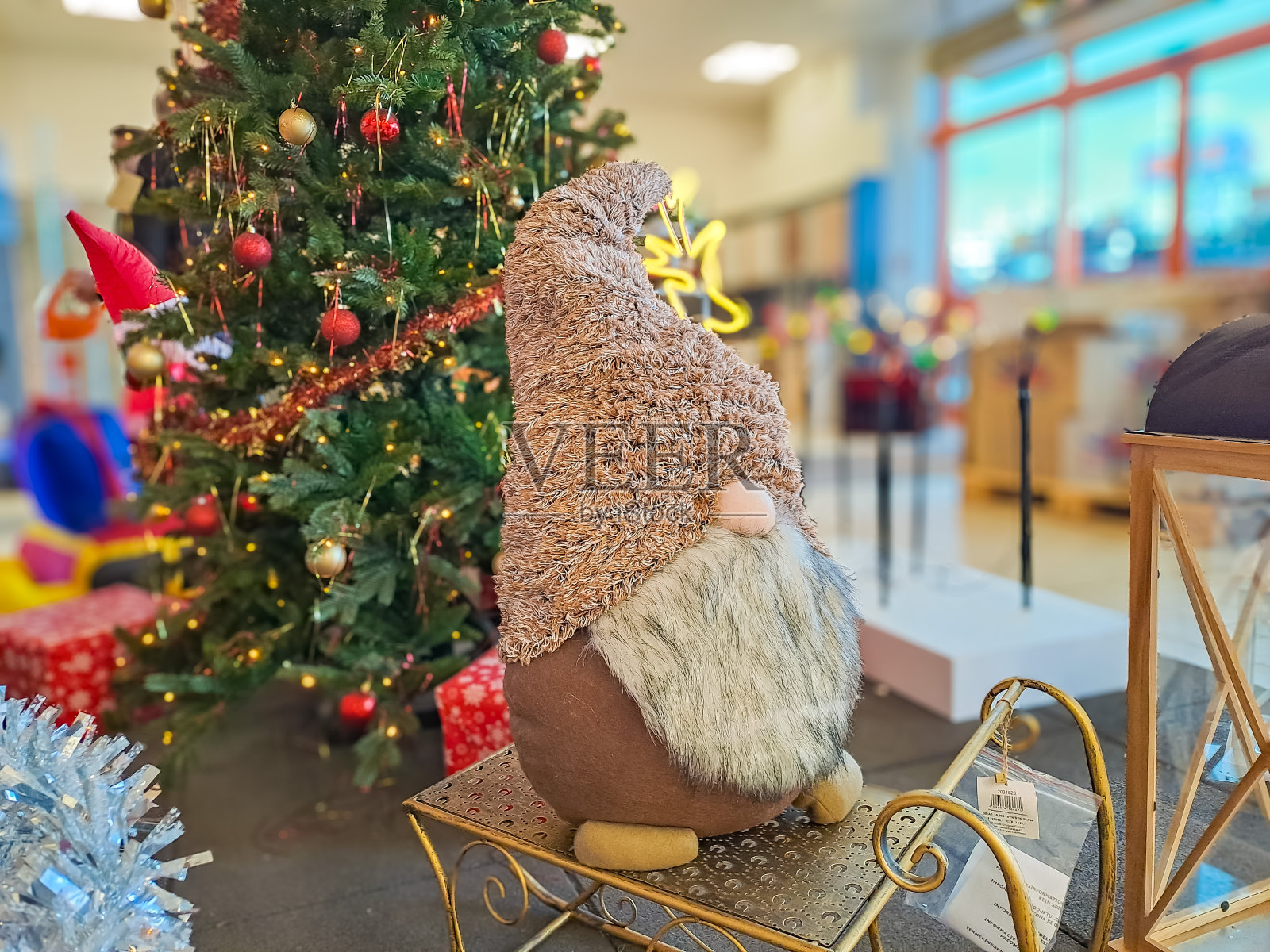 圣诞树下的小妖精。戴着米色帽子的节日玩具。照片摄影图片