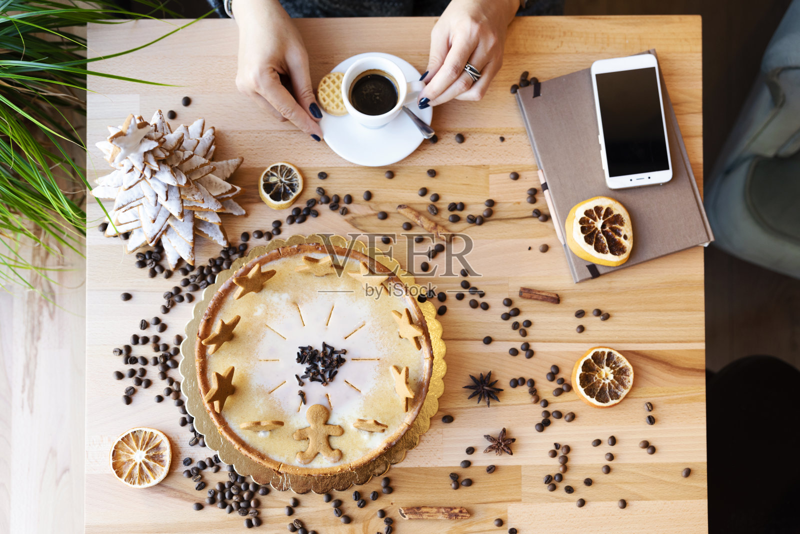 食物和饮料。女人和一杯黑咖啡，甜蛋糕和圣诞树。屏幕放在桌子上的智能手机。以上。照片摄影图片