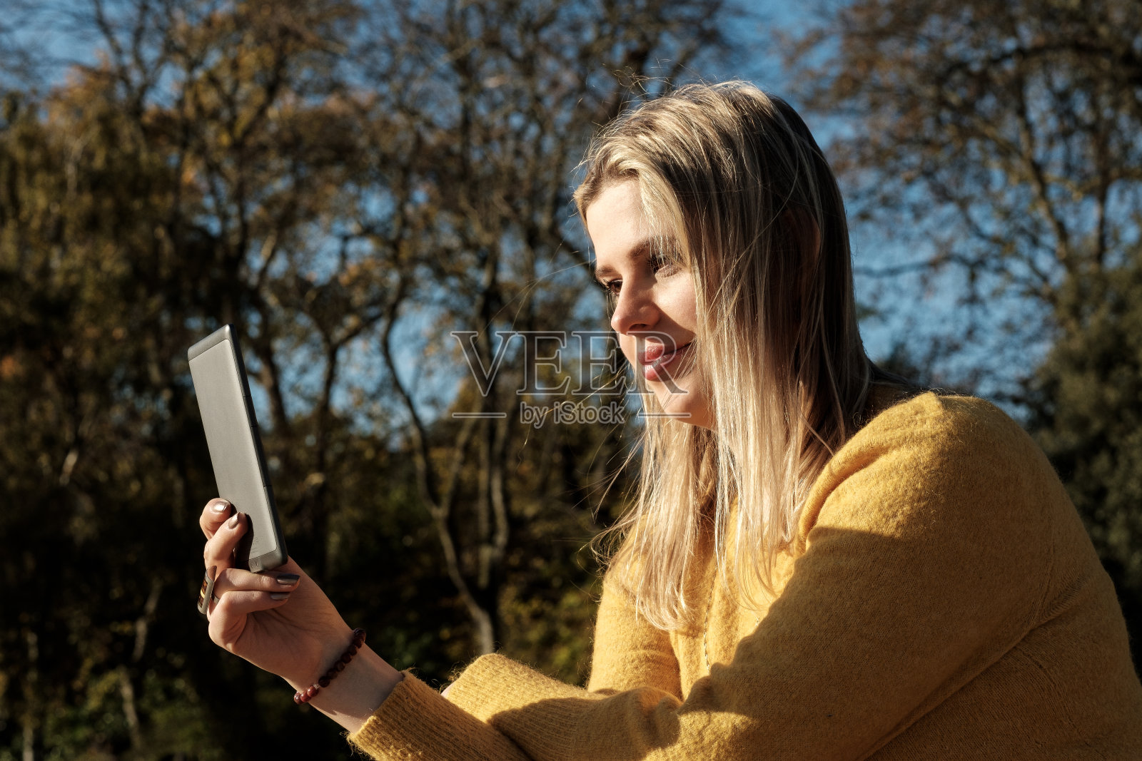 年轻女子在森林里使用电子阅读器。照片摄影图片
