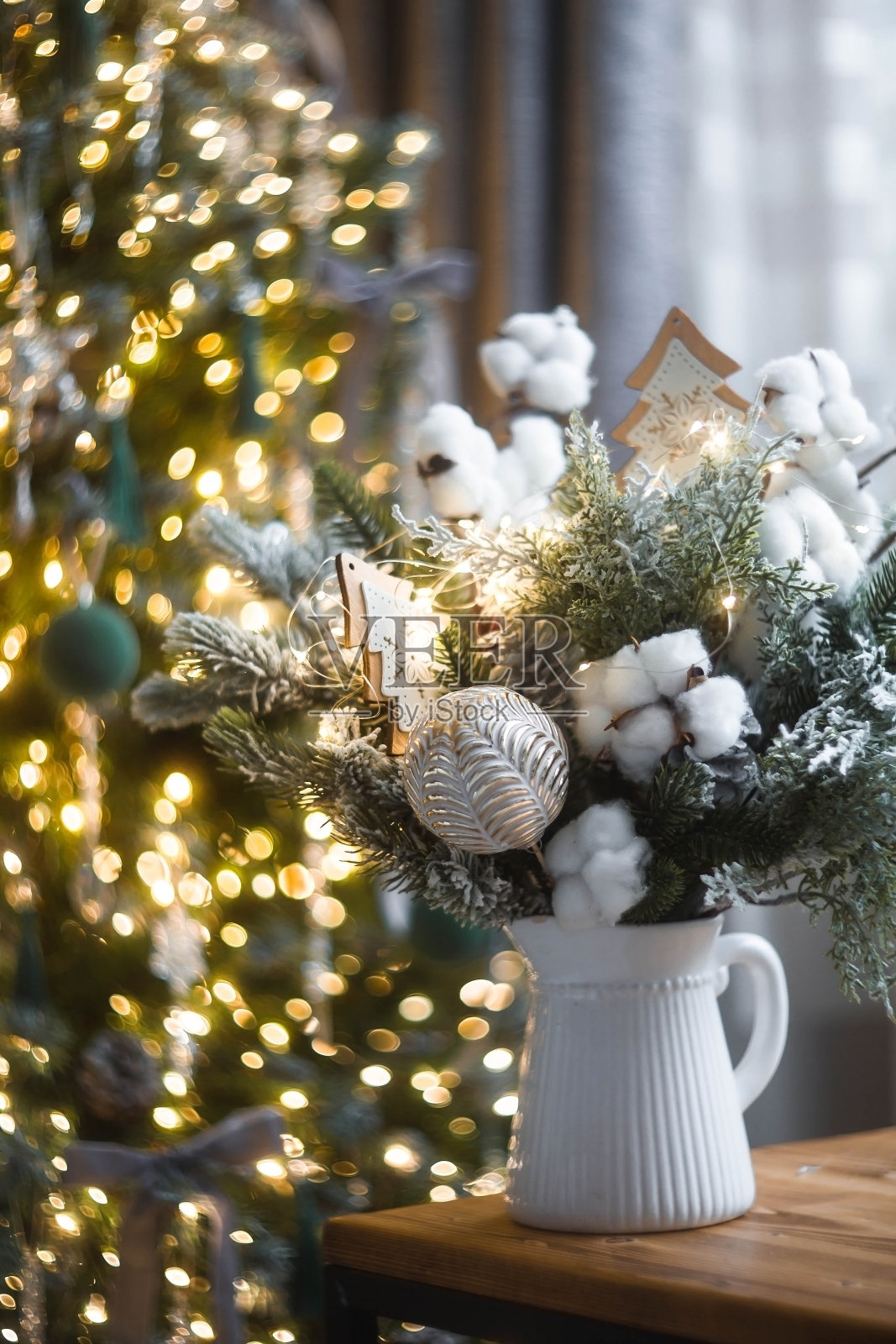 桌上放着一束冷杉树、棉花和玩具，背景是圣诞树上的花环。室内的冬季装饰。2024年新年假期的概念。照片摄影图片