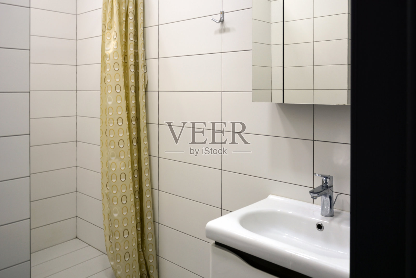 简单的家庭淋浴浴室，水槽，水龙头和镜子。墙上有瓷砖照片摄影图片