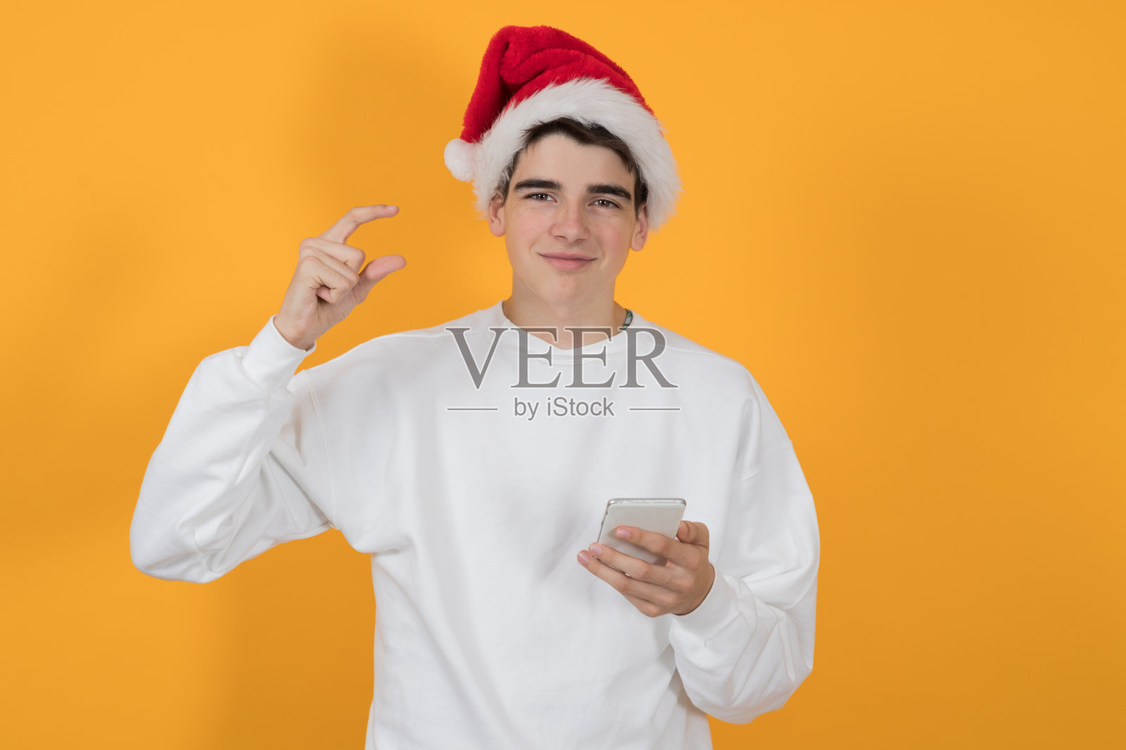 年轻人戴着圣诞老人的帽子，孤立的彩色背景照片摄影图片