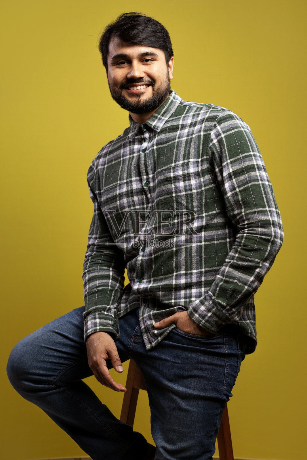 一个人坐在那里，面带微笑，手插在口袋里照片摄影图片