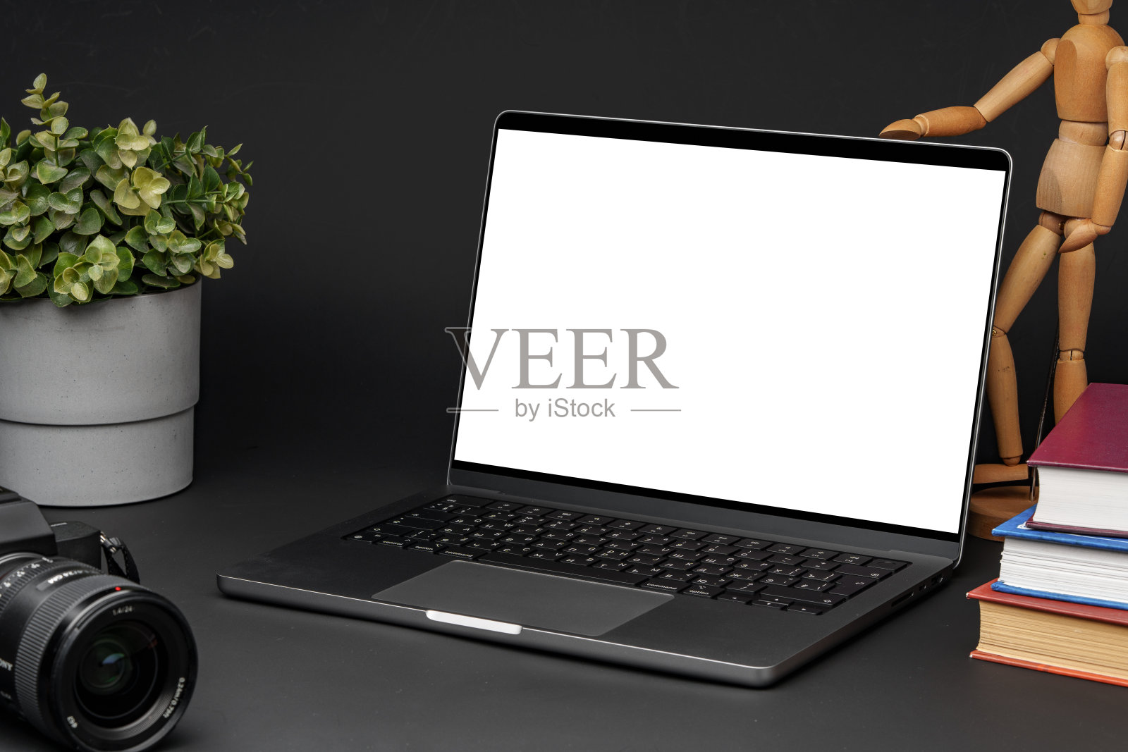 打开笔记本电脑，黑色背景的桌子上放着木制的人体模型照片摄影图片