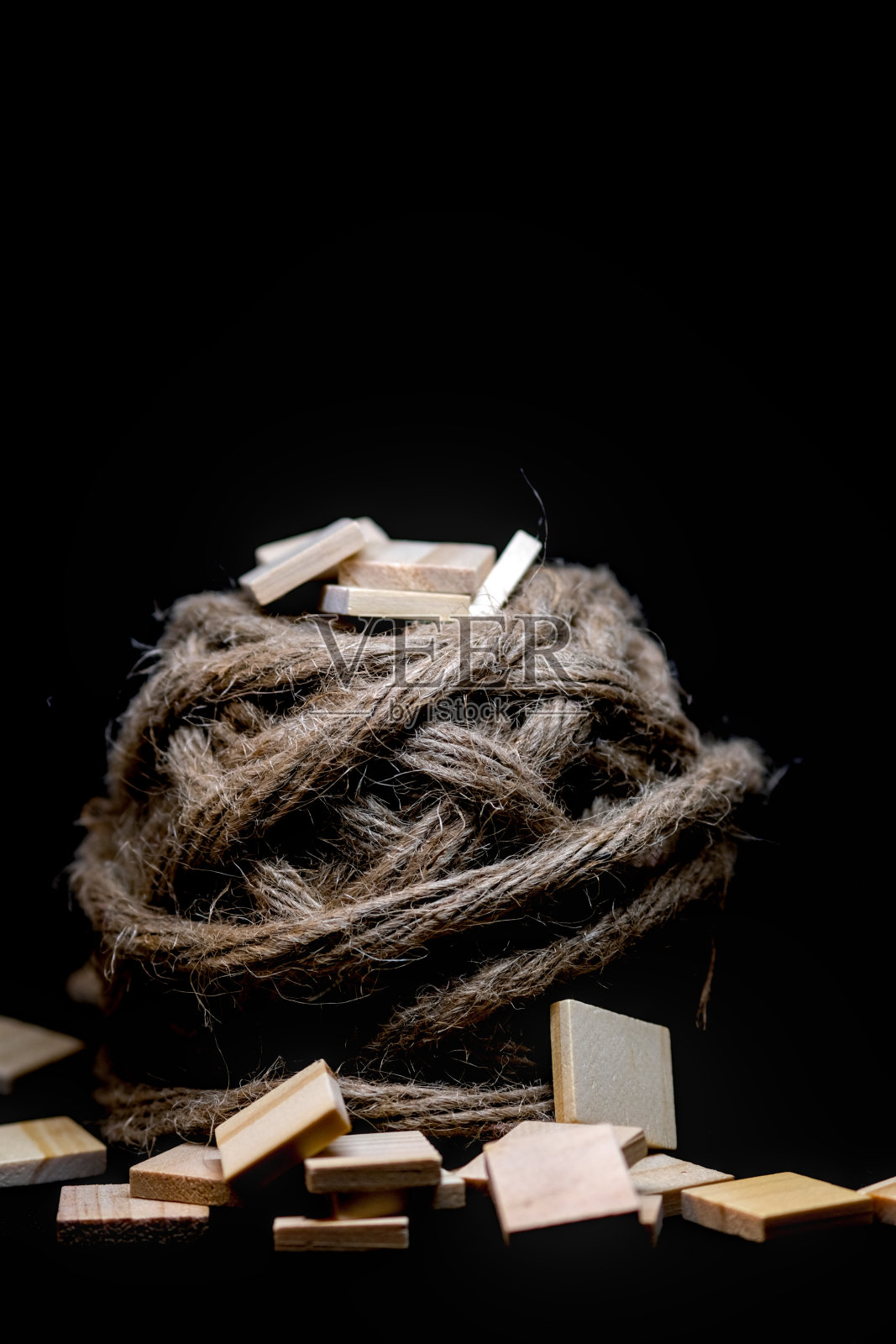 在黑色背景上，靠近麻线球的一堆木方块。照片摄影图片