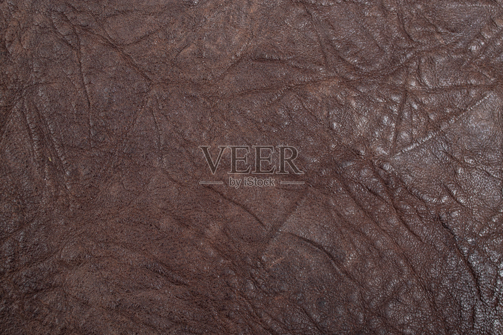粗糙的棕色皮革纹理带有褶皱，动物皮肤表面作为深色抽象背景，近距离观察照片摄影图片