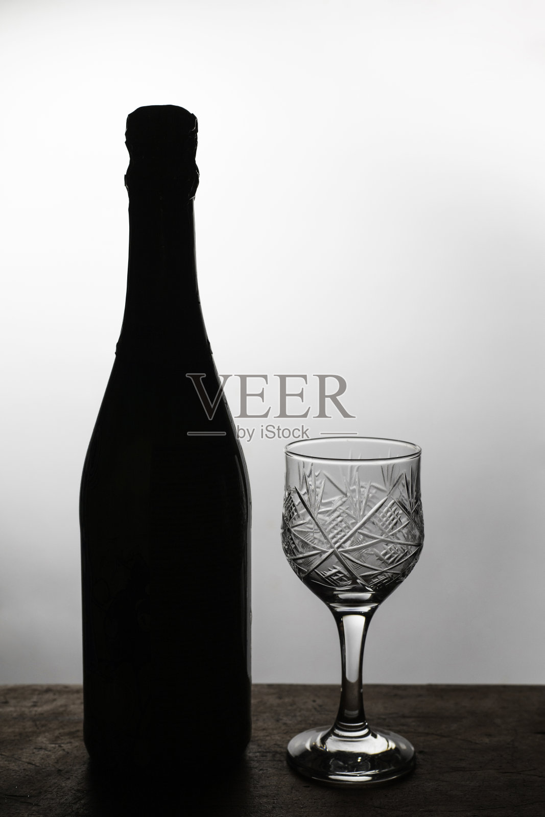 漂亮的玻璃杯和香槟酒放在一张旧木桌上。背光剪影。新年假期和庆祝背景与复制空间。照片摄影图片