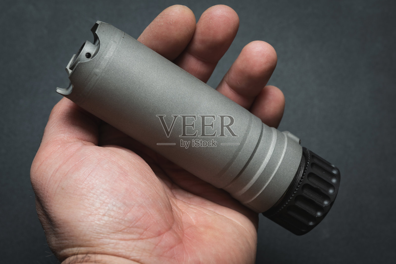 一个男人手里拿着步枪的消音器，特写照片。照片摄影图片