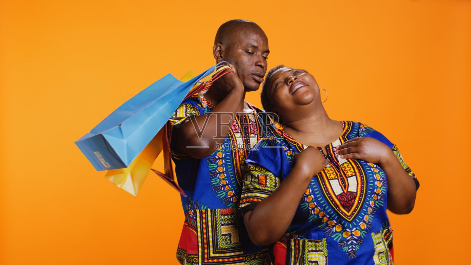 无聊的丈夫为他快乐的妻子提着购物袋照片摄影图片