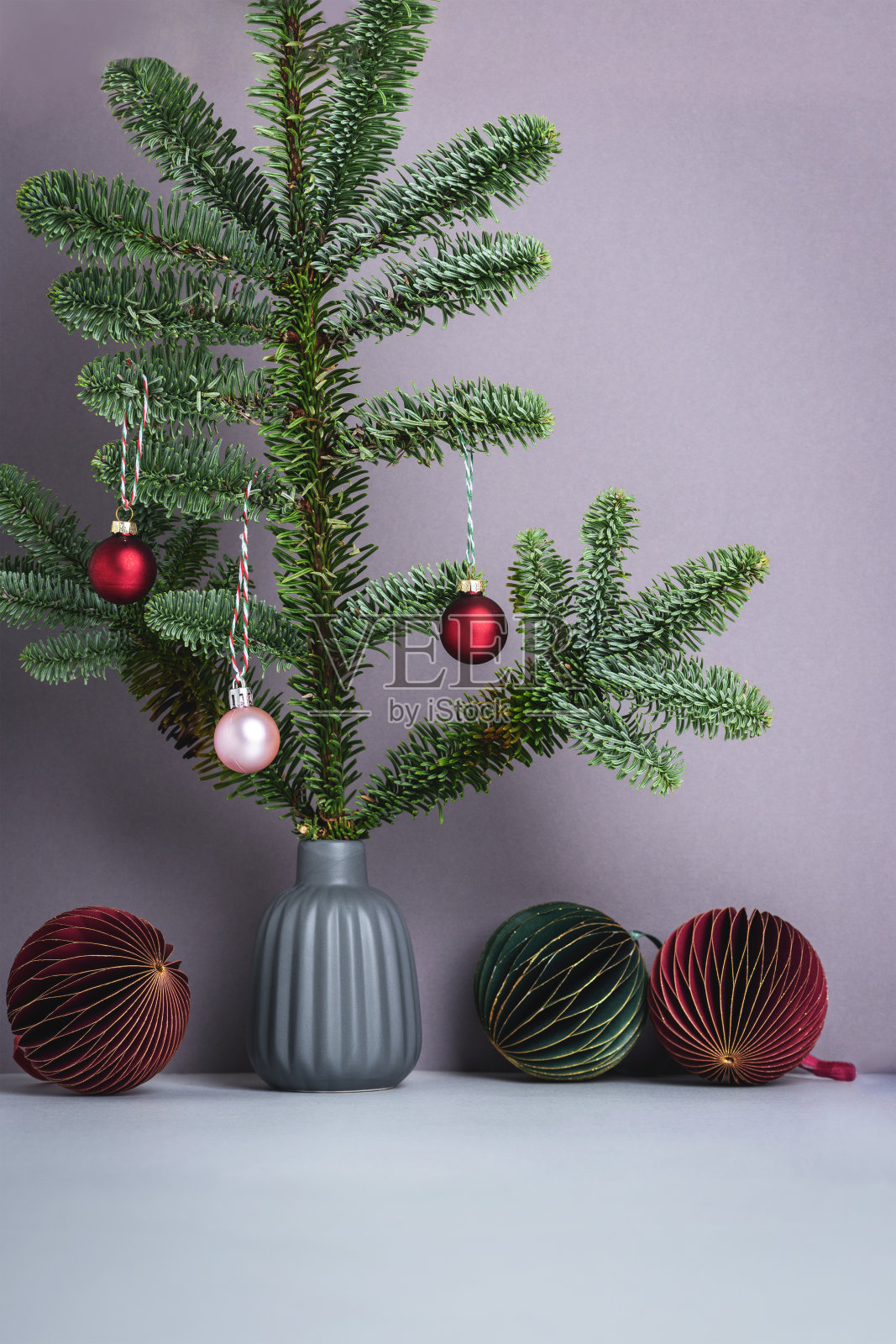 灰色花瓶与冷杉枝和纸圣诞树装饰在灰色的背景。贺卡，新年概念。前视图照片摄影图片