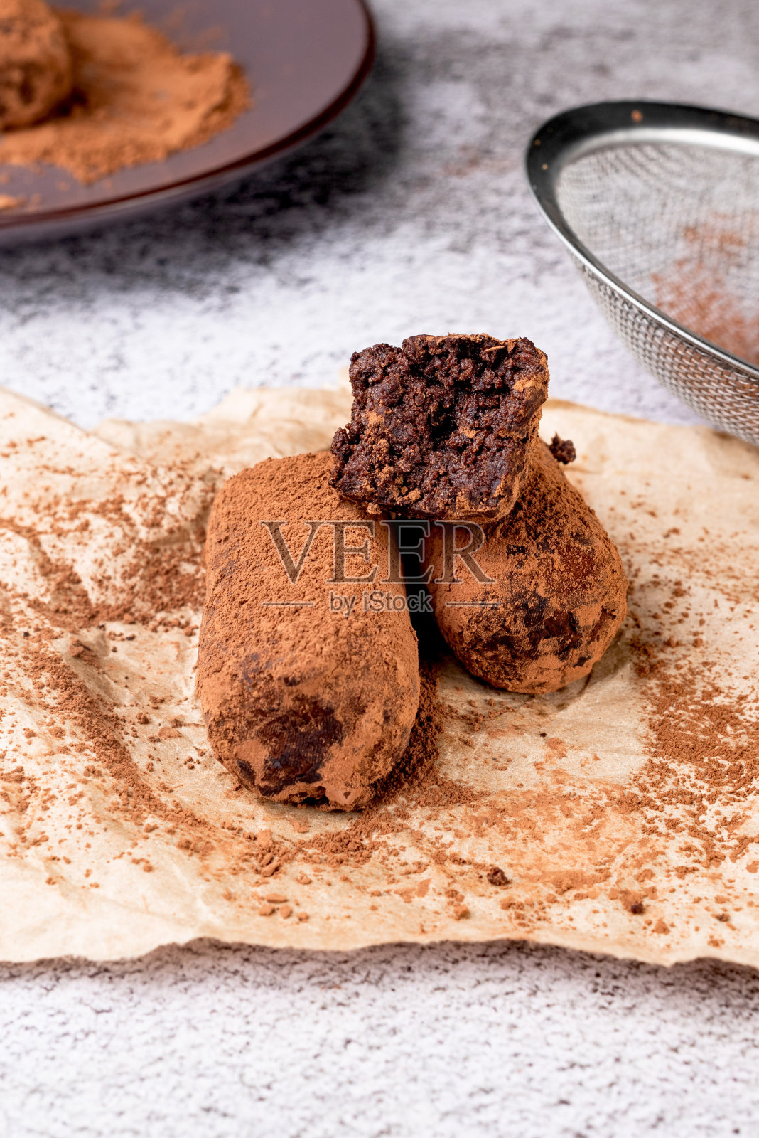 巧克力土豆蛋糕。盘中有奶油和可可粉的饼干。松露甜点，撒上可可粉，照片摄影图片