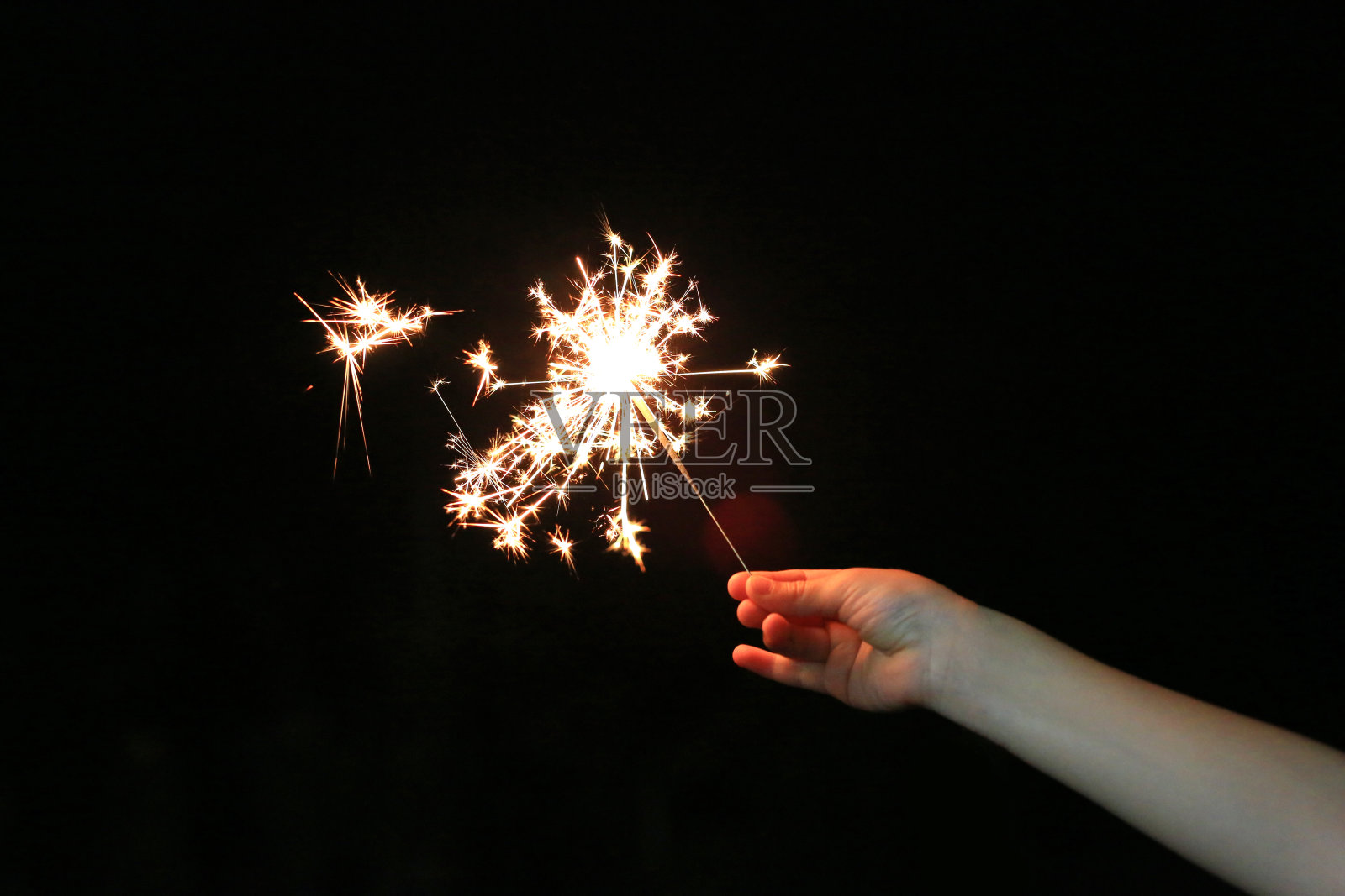 在黑暗的节日里，小孩手拿着烟火。照片摄影图片