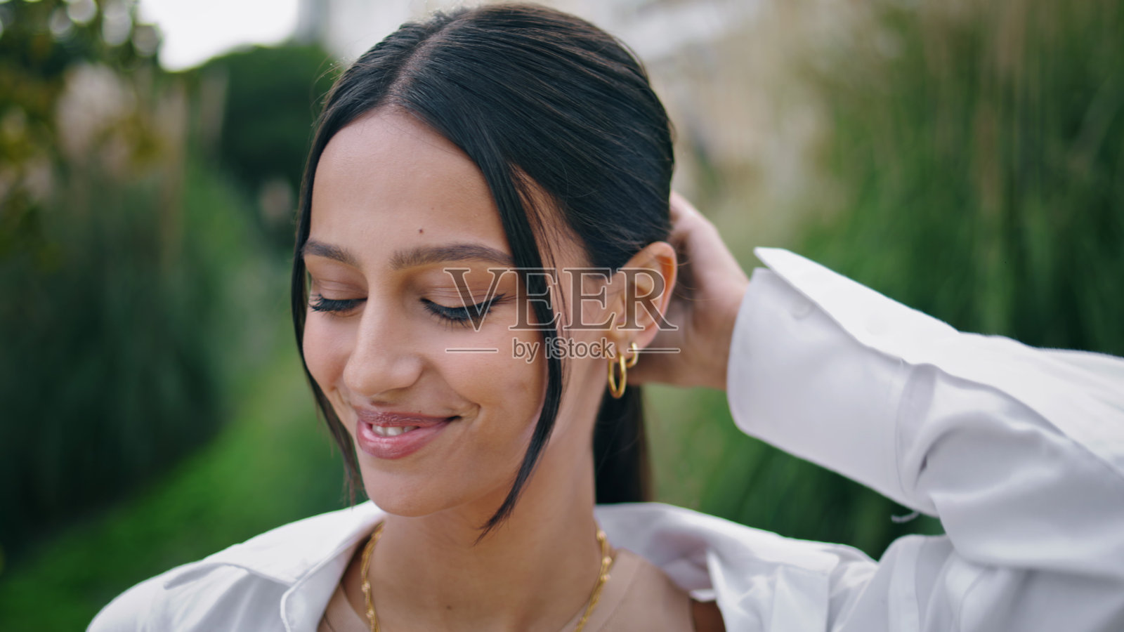 肖像快乐的女人摆姿势公园。微笑的女士看着镜头纠正头发照片摄影图片