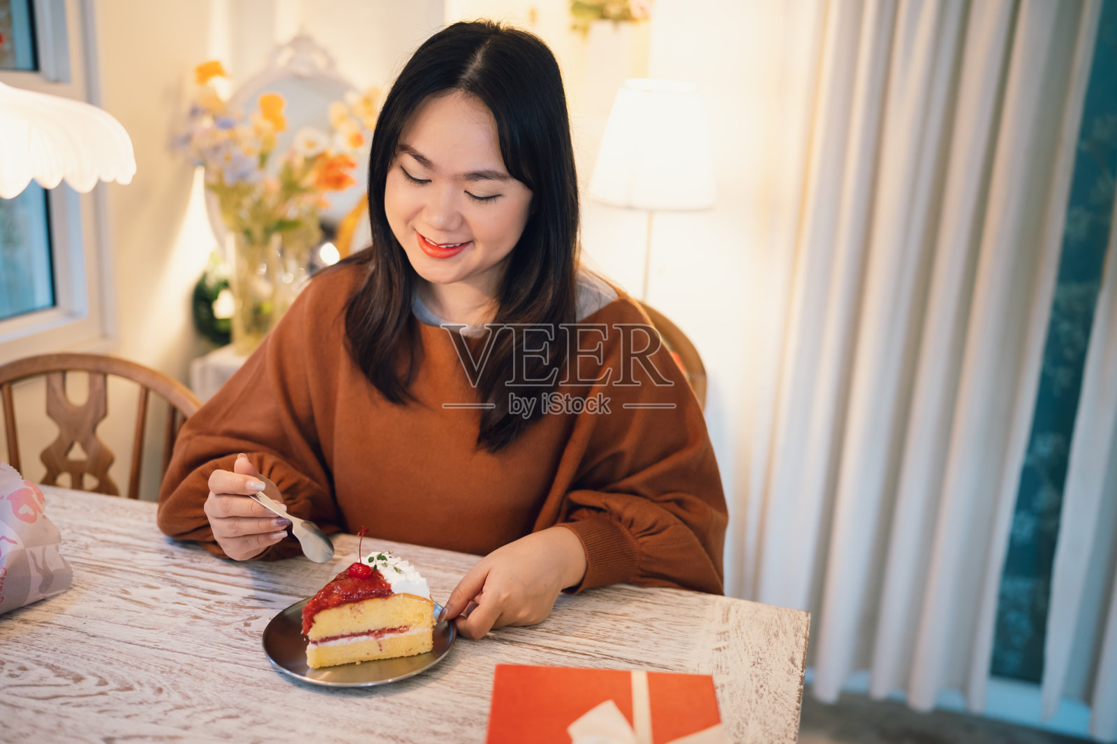 快乐的亚洲妇女吃美味的圣诞fruitÂ蛋糕。圣诞晚餐派对配上美味的圣诞蛋糕，有新年和圣诞的概念照片摄影图片