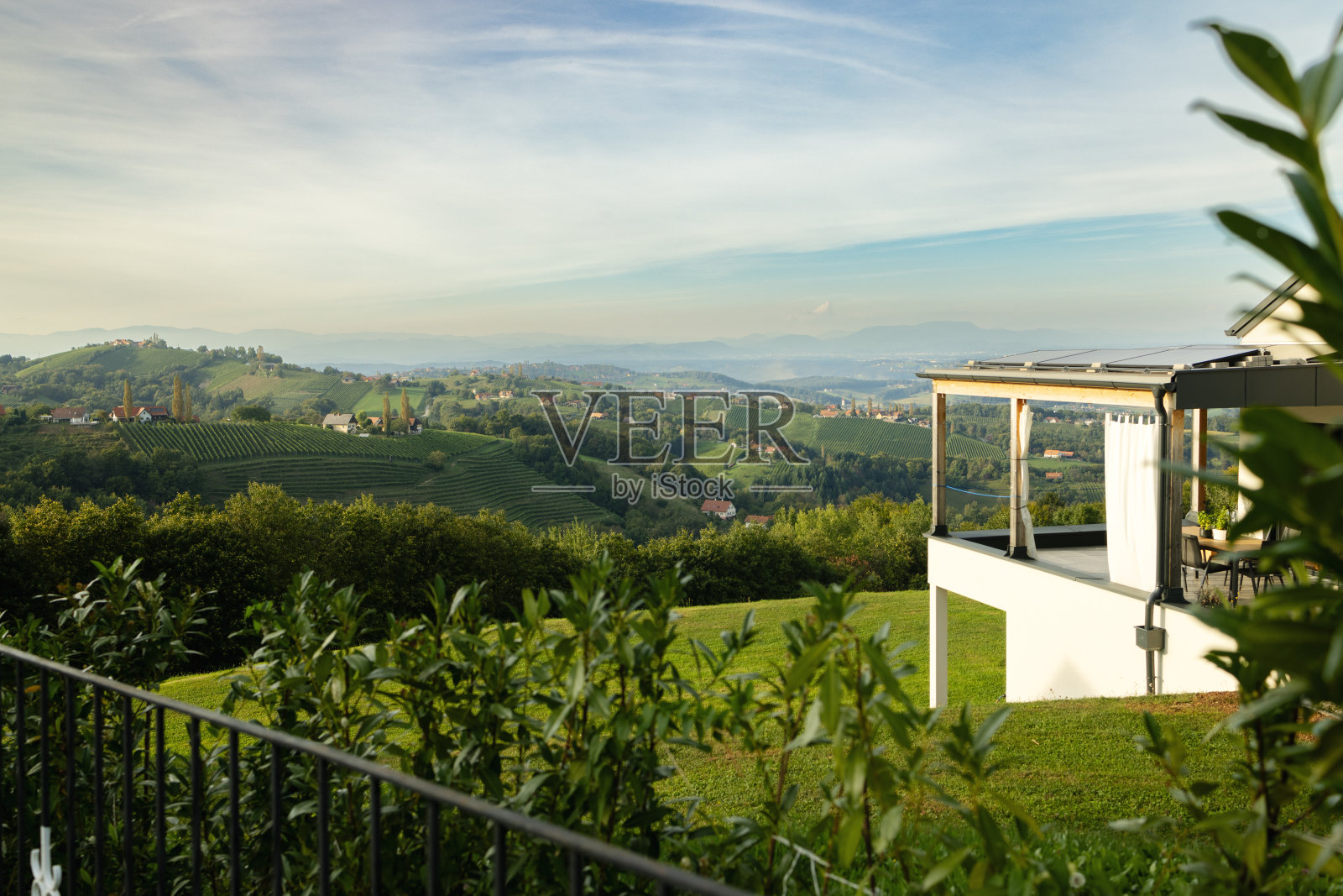 丘陵夏季景观与葡萄园和村庄在奥地利。房子的室外露台在楼上照片摄影图片
