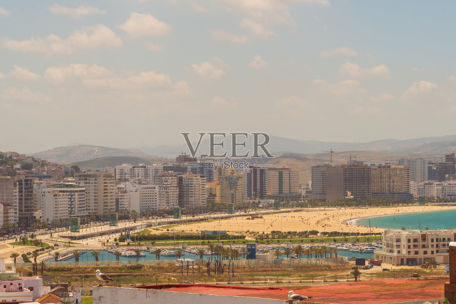 城市全景，沙滩和海滨度假者与城市发展，山和云与蓝天照片摄影图片