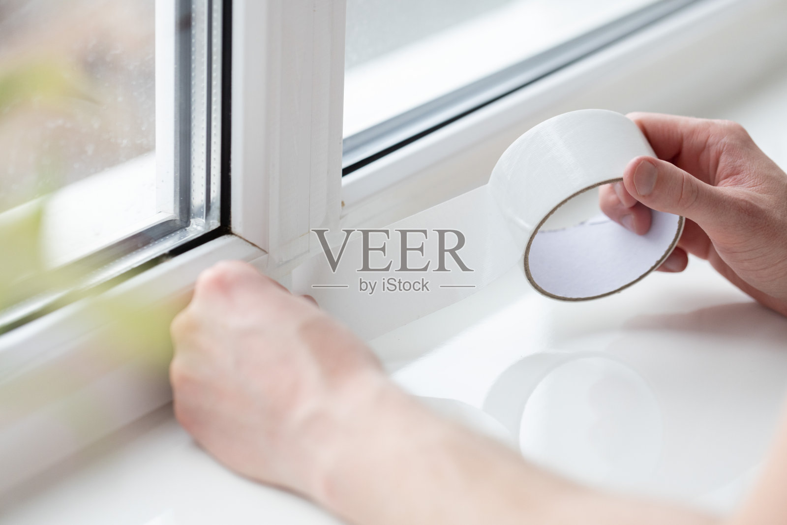 有人在窗户上贴防风胶带，防止风吹进来。照片摄影图片