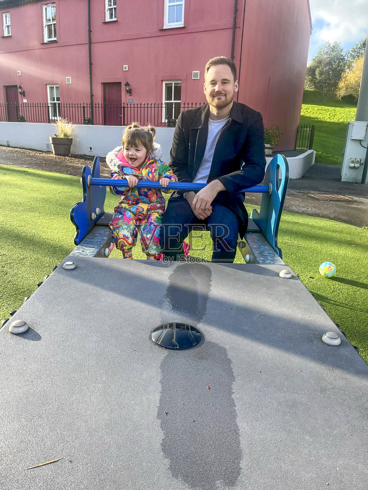 父亲和蹒跚学步的女儿玩跷跷板照片摄影图片