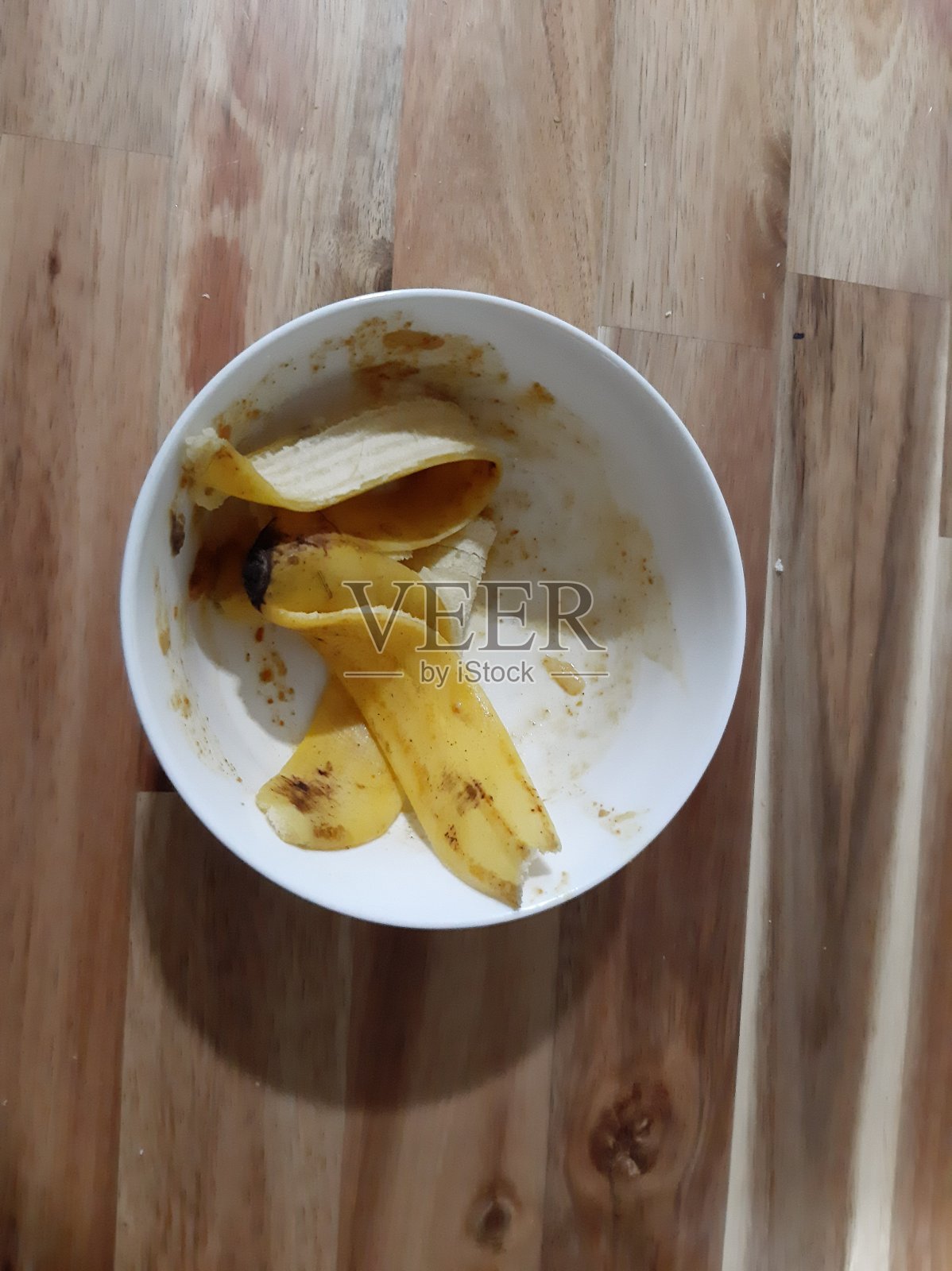木制背景碗里的碎香蕉皮。前视图。照片摄影图片