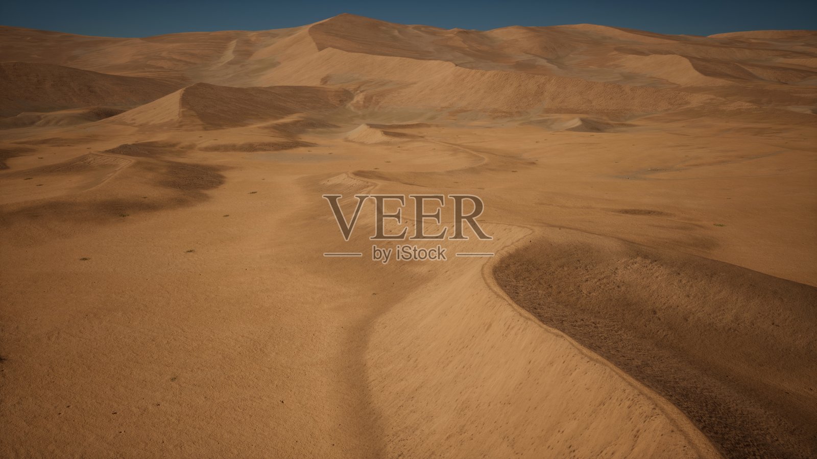 广阔的沙漠地形，金色的沙子映衬着蔚蓝的天空。照片摄影图片
