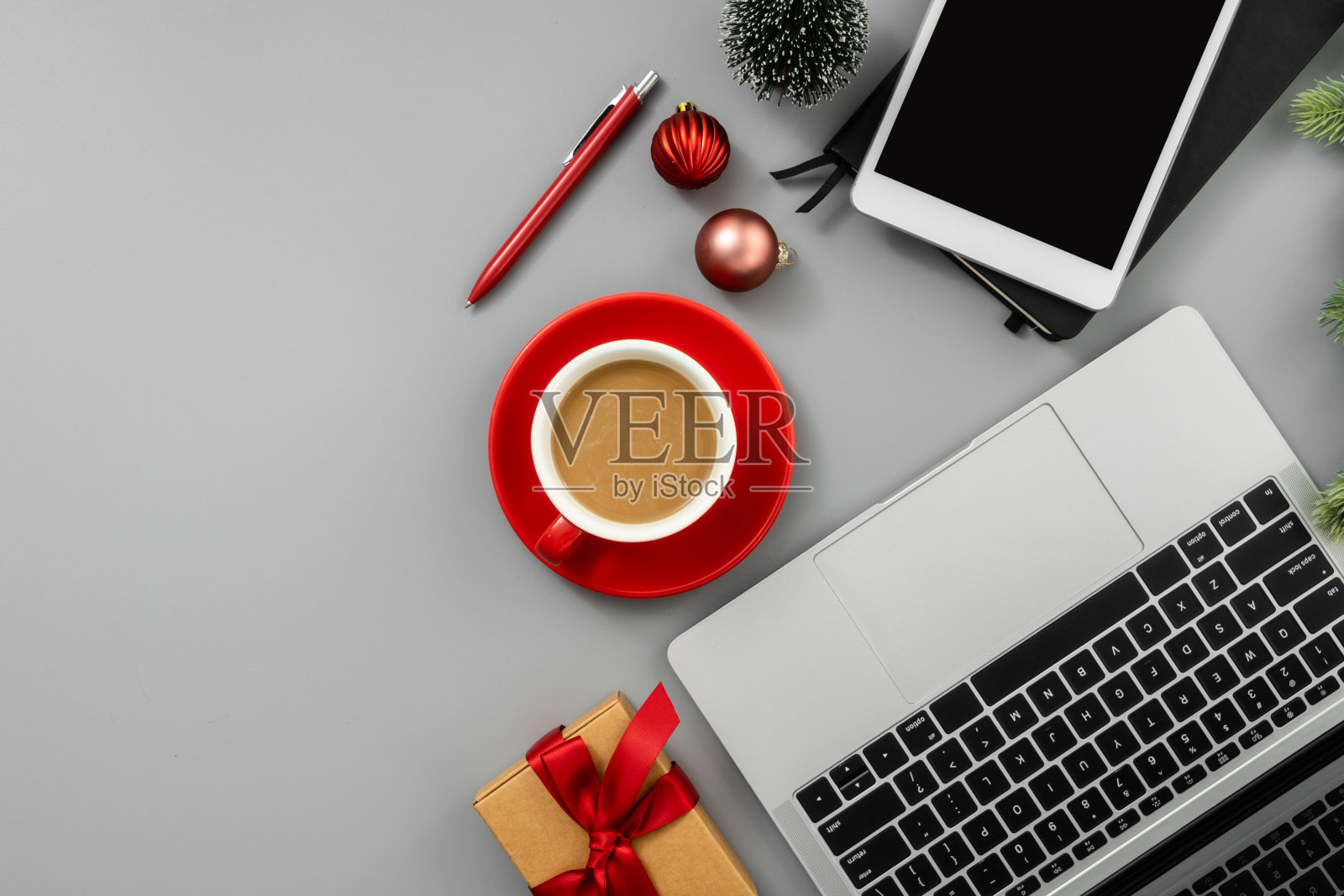 灰色办公桌子，笔记本电脑，记事本，数码平板电脑，一杯咖啡和圣诞装饰品。照片摄影图片