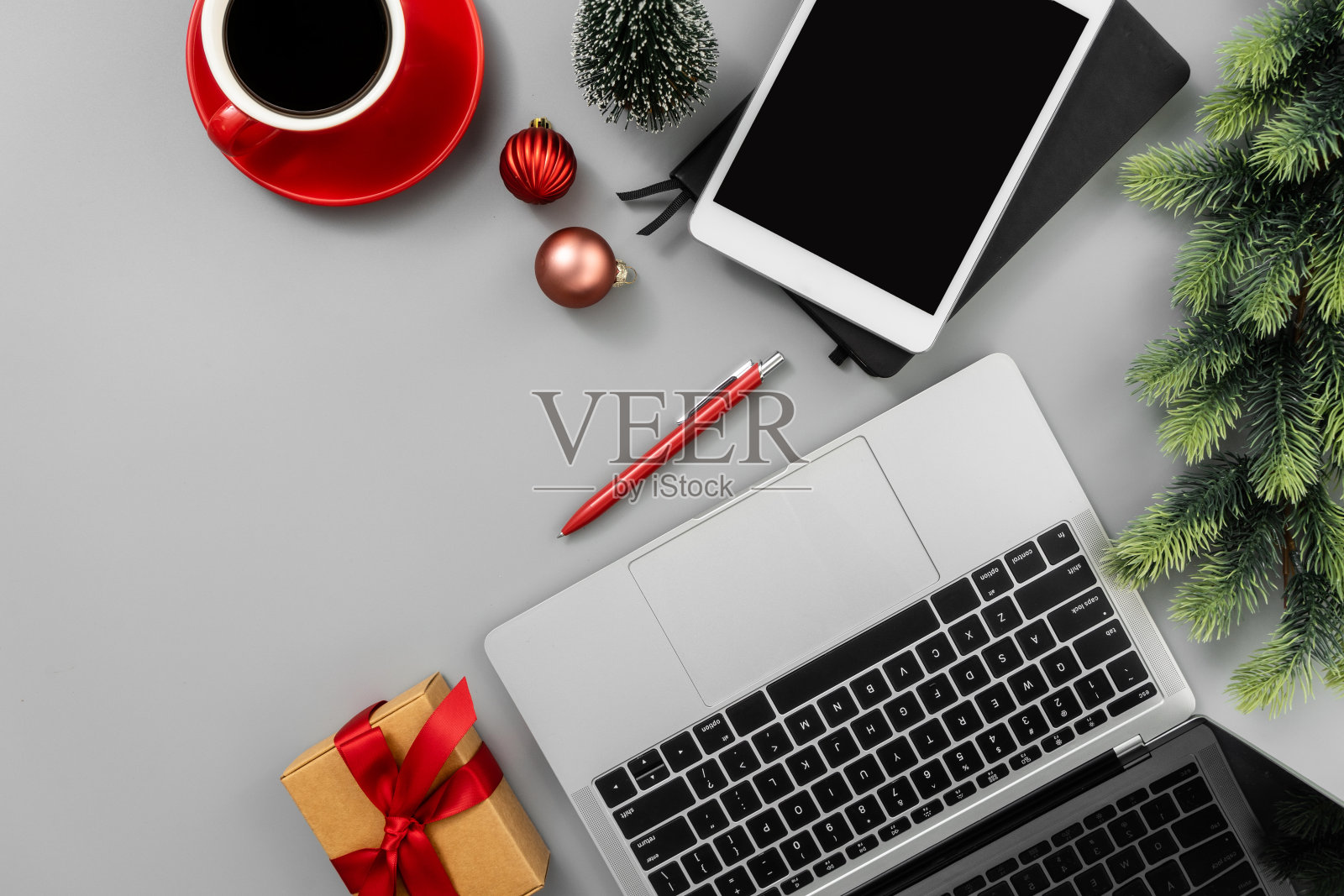 灰色办公桌子，笔记本电脑，记事本，数码平板电脑，一杯咖啡和圣诞装饰品。照片摄影图片