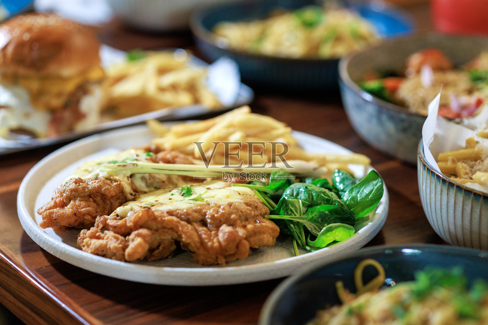 餐馆里的一盘脆脆的炸鸡，慷慨地点缀着一层诱人的融化奶酪，创造了一道开胃可口的菜肴。照片摄影图片