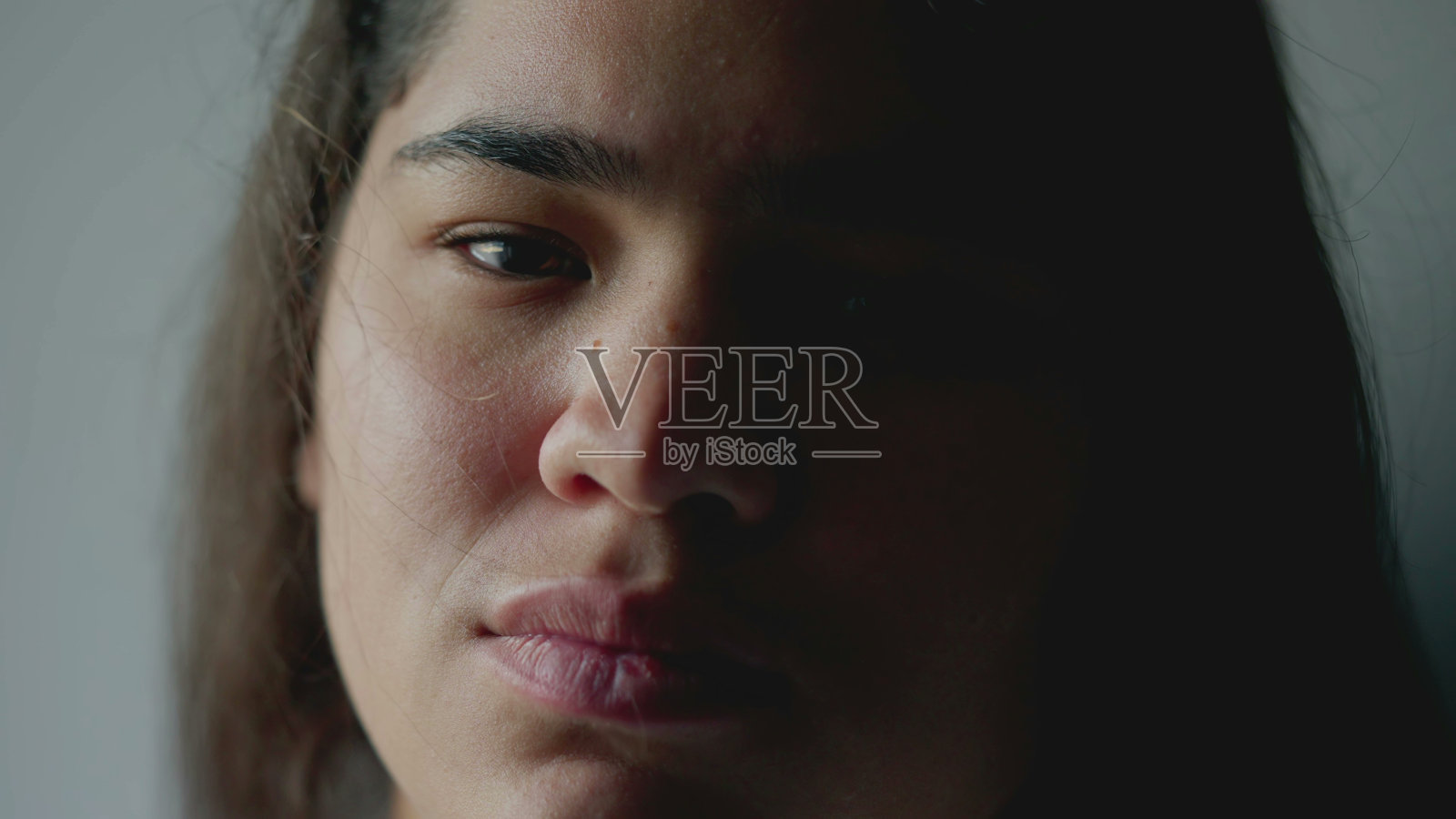 一个多种族年轻女子的特写脸，带着严肃的表情看着镜头。一个20多岁的巴西南美成年女孩照片摄影图片