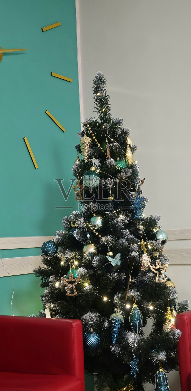 圣诞树上有金色的大钟和红色的椅子照片摄影图片