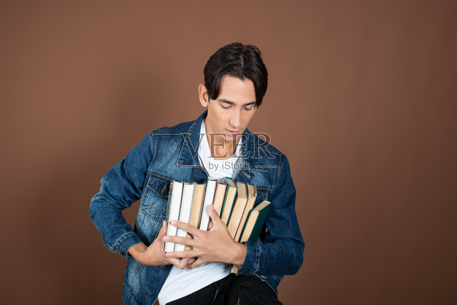 年轻人和学习。有趣的帅哥在棕色背景上摆姿势。照片摄影图片