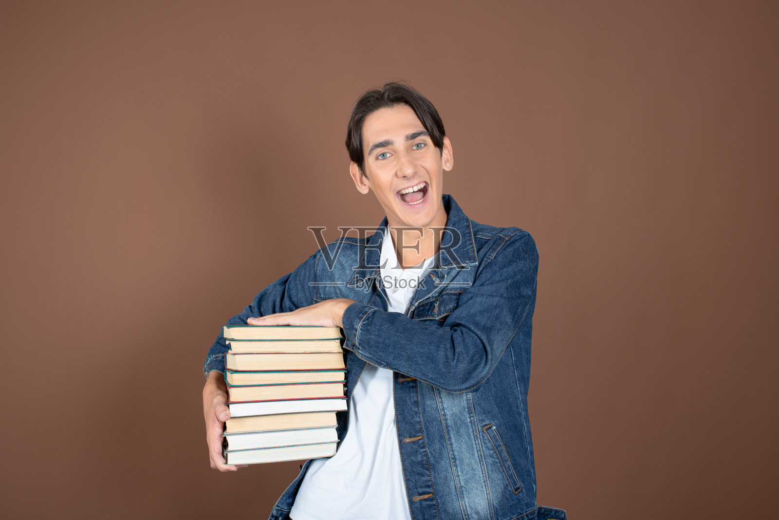 年轻人和学习。有趣的帅哥在棕色背景上摆姿势。照片摄影图片