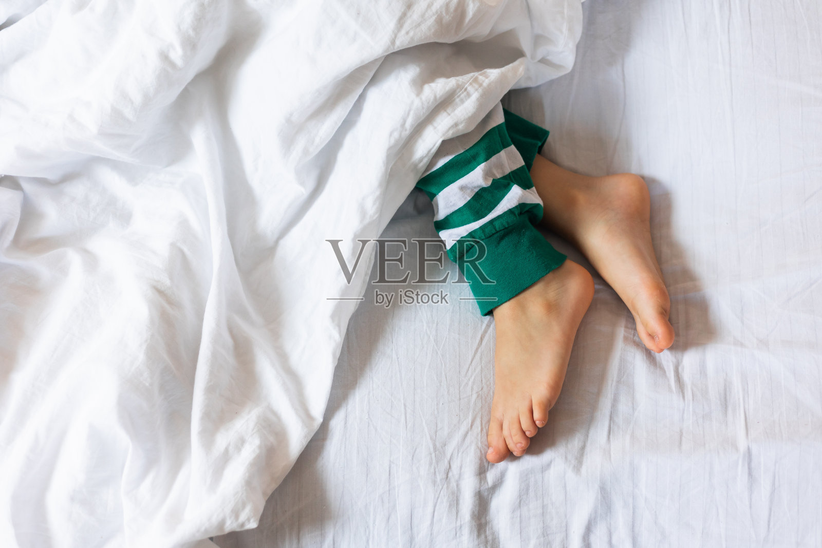 白毯子下的孩子的脚。复制空间和空白空间的文本，模型照片摄影图片