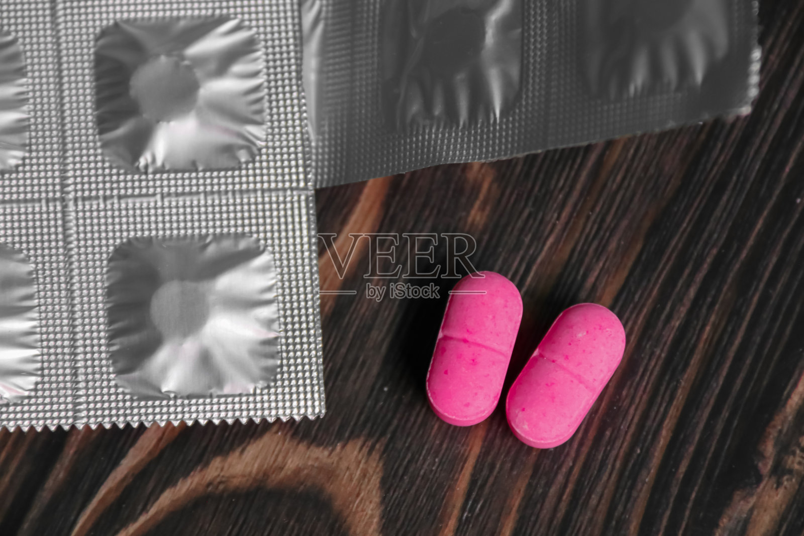 木制背景上的两颗粉色药丸照片摄影图片