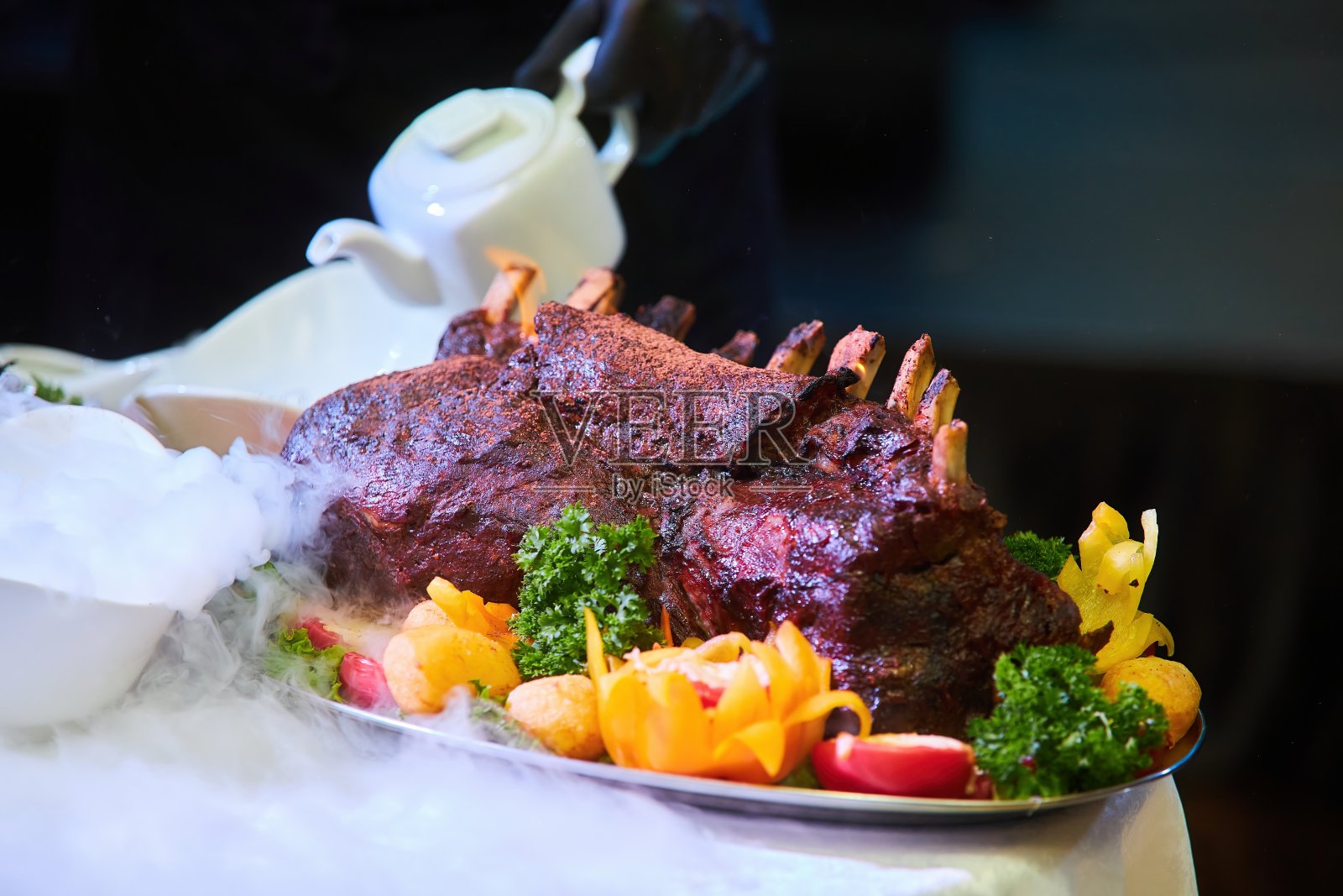 厨师在客人面前煮肉。餐馆里的荤菜。照片摄影图片