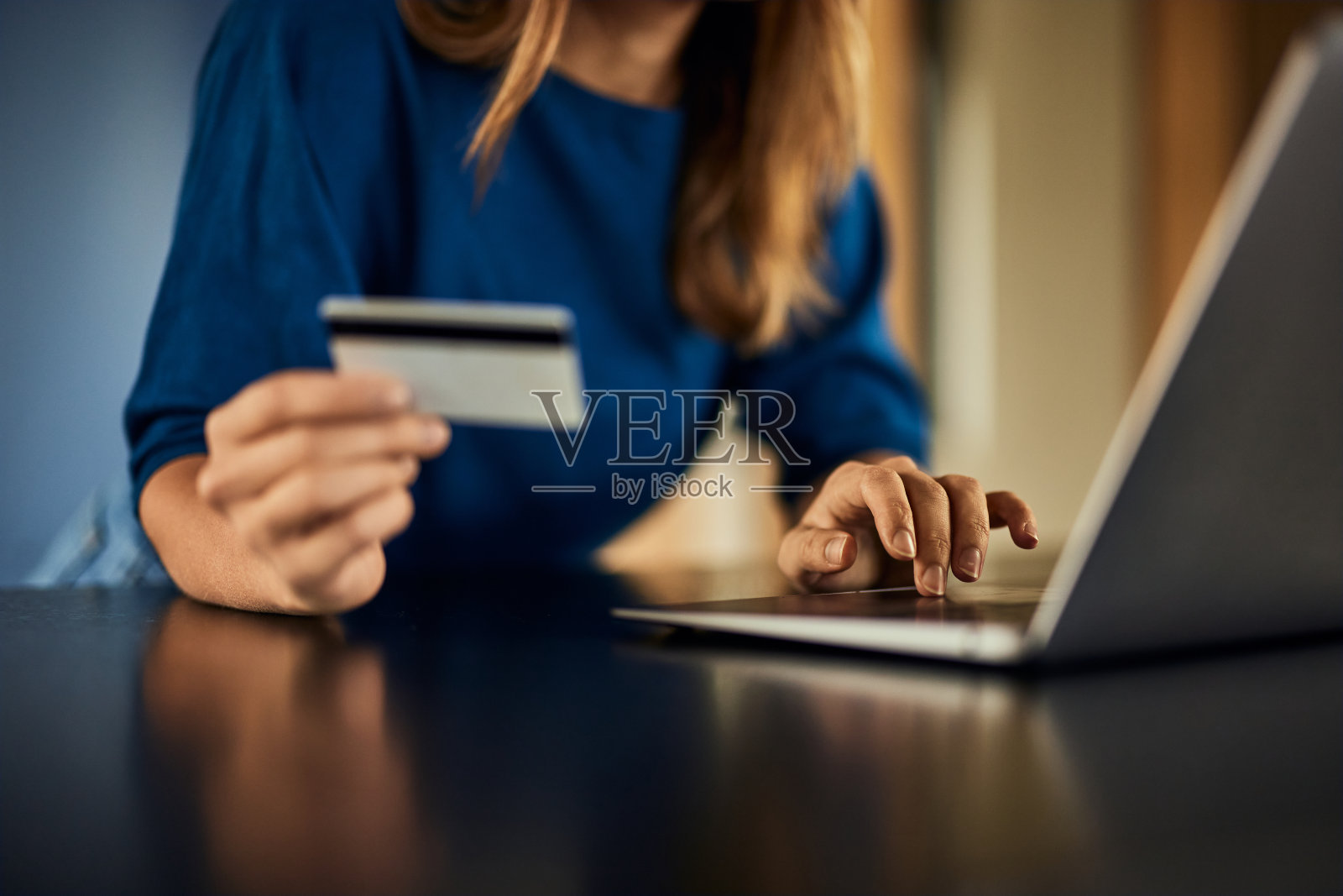 一个女性手的特写，拿着信用卡，用笔记本电脑网购。照片摄影图片