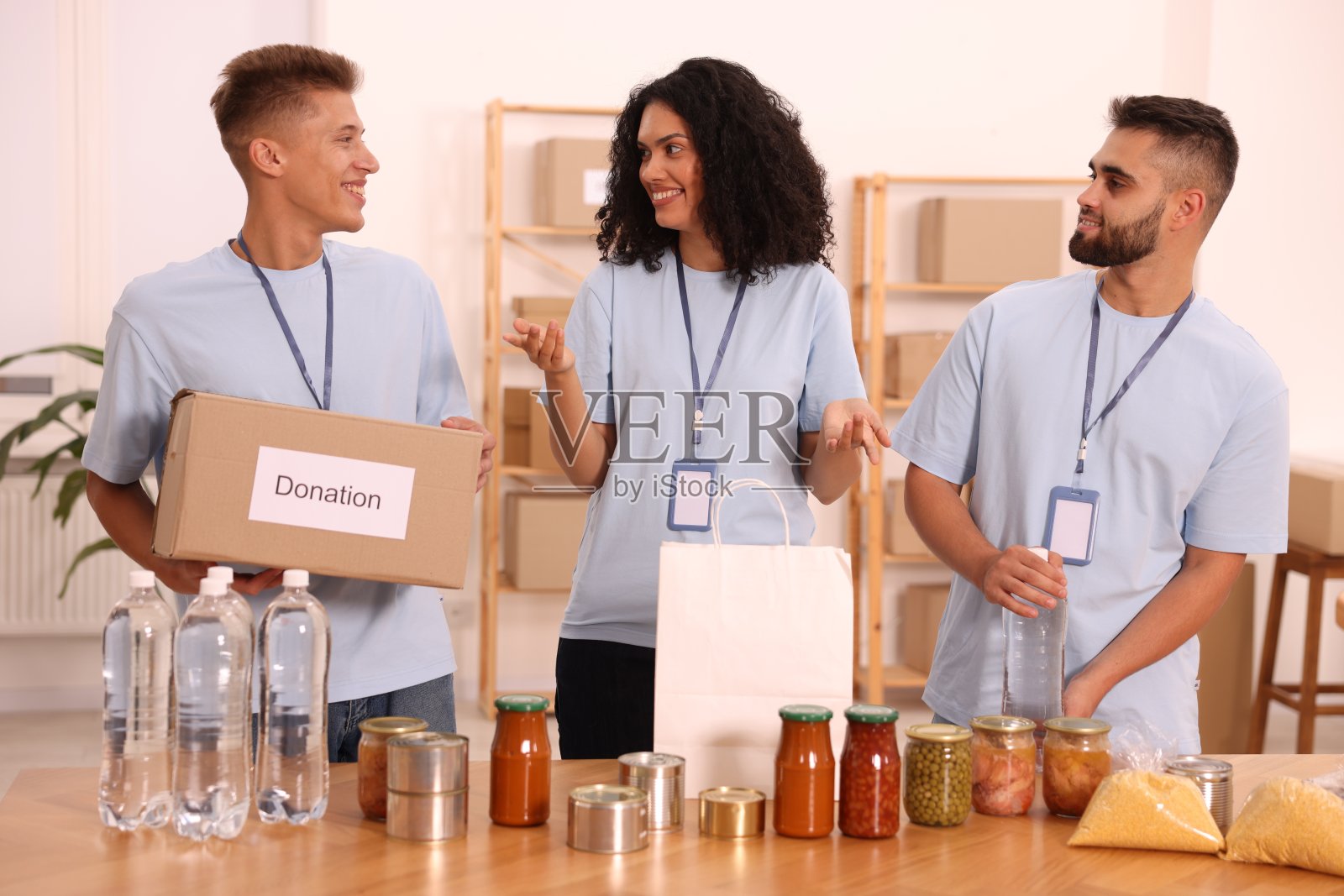 一群志愿者在仓库的桌子上拿着捐款箱、纸袋和食品照片摄影图片