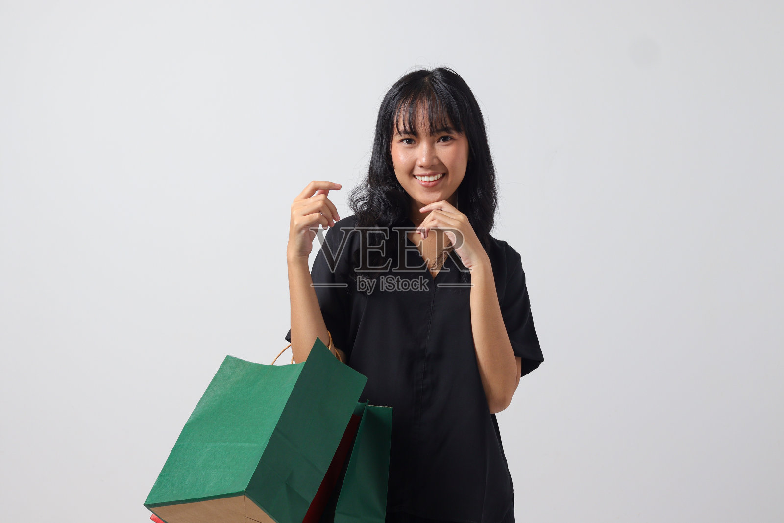 兴奋的亚洲妇女穿着黑色衬衫，拿着五颜六色的纸质购物袋。购物狂和折扣购物概念。白色背景上的孤立图像照片摄影图片