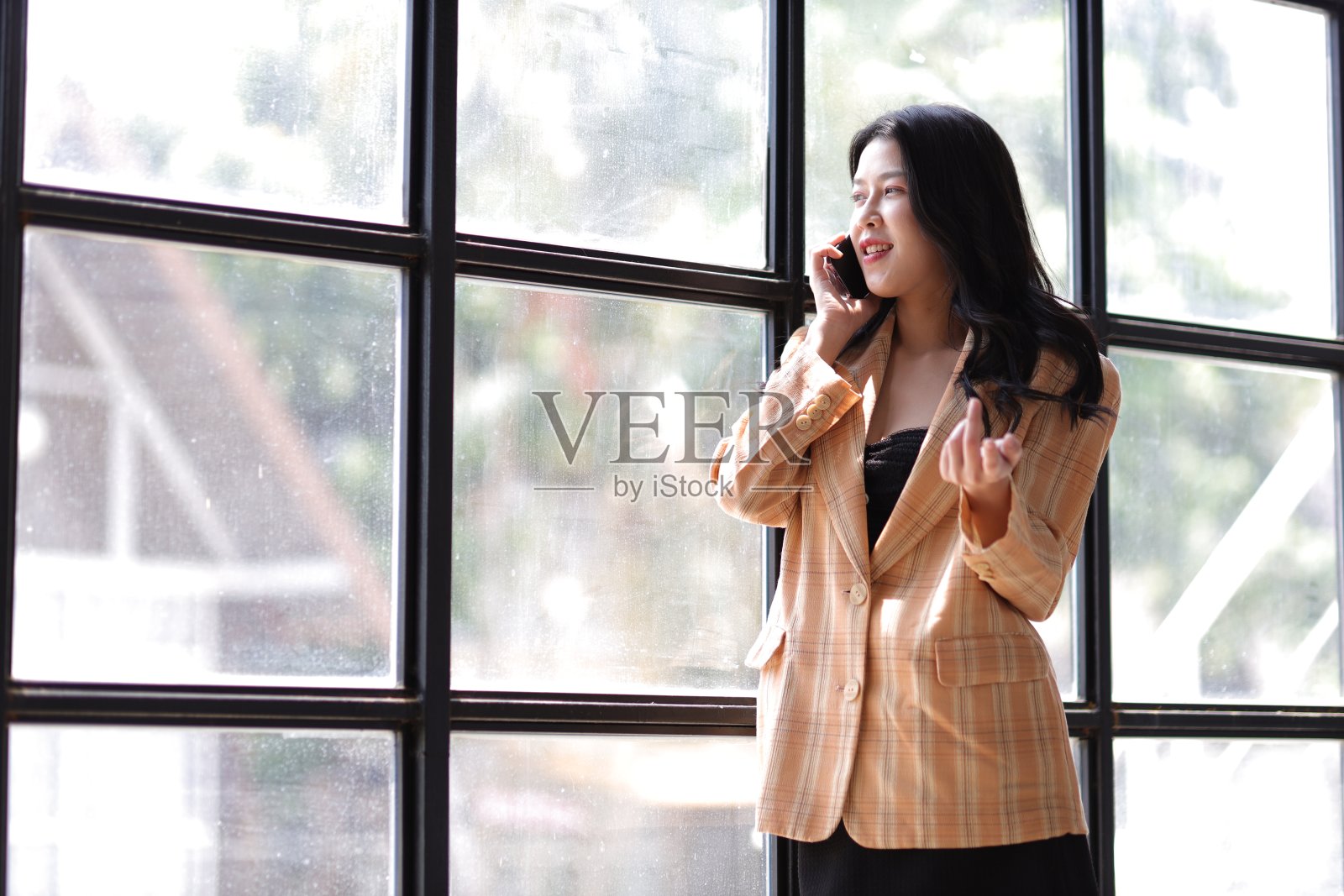 有吸引力和性感的年轻女商人在办公室用手机打电话与同事和商业伙伴。照片摄影图片