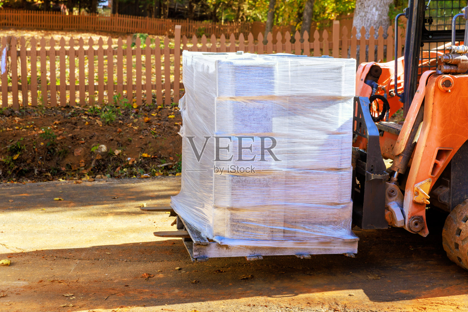 一名工人用小型拖拉机卸载挡土墙用的托盘混凝土块照片摄影图片