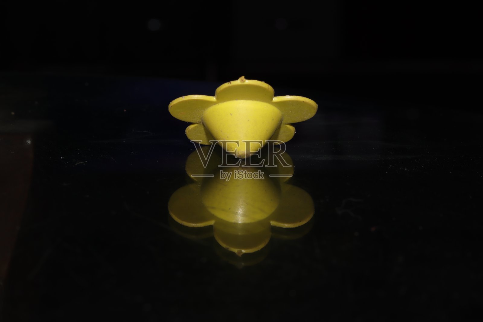 一个小花形的塑料手旋转顶部玩具在一个黑色孤立的背景，反射照片摄影图片