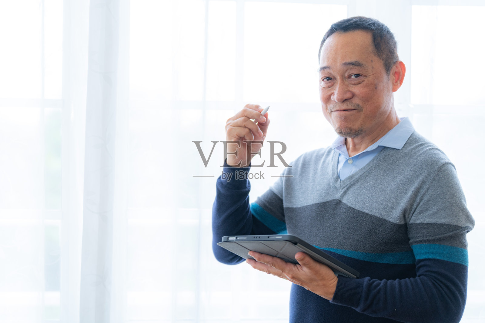 男性老年人通过智能平板电脑视频通话的幸福感。老人们在客厅里谈笑风生。快乐的退休朋友享受放松。照片摄影图片