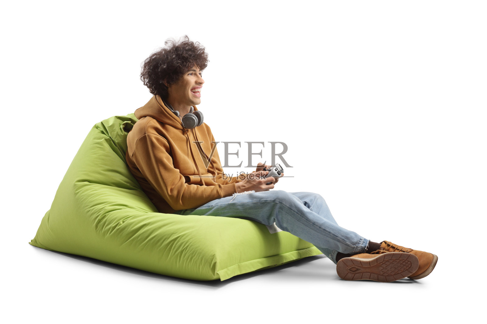 一个家伙坐在绿色的豆袋扶手椅上，用操纵杆玩游戏照片摄影图片