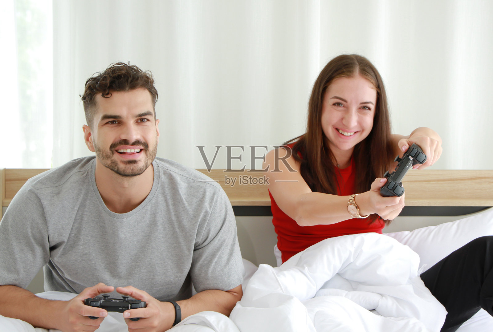 一对夫妇在卧室里手握操纵杆，一起玩游戏。生活方式关系婚恋度假生活的概念照片摄影图片