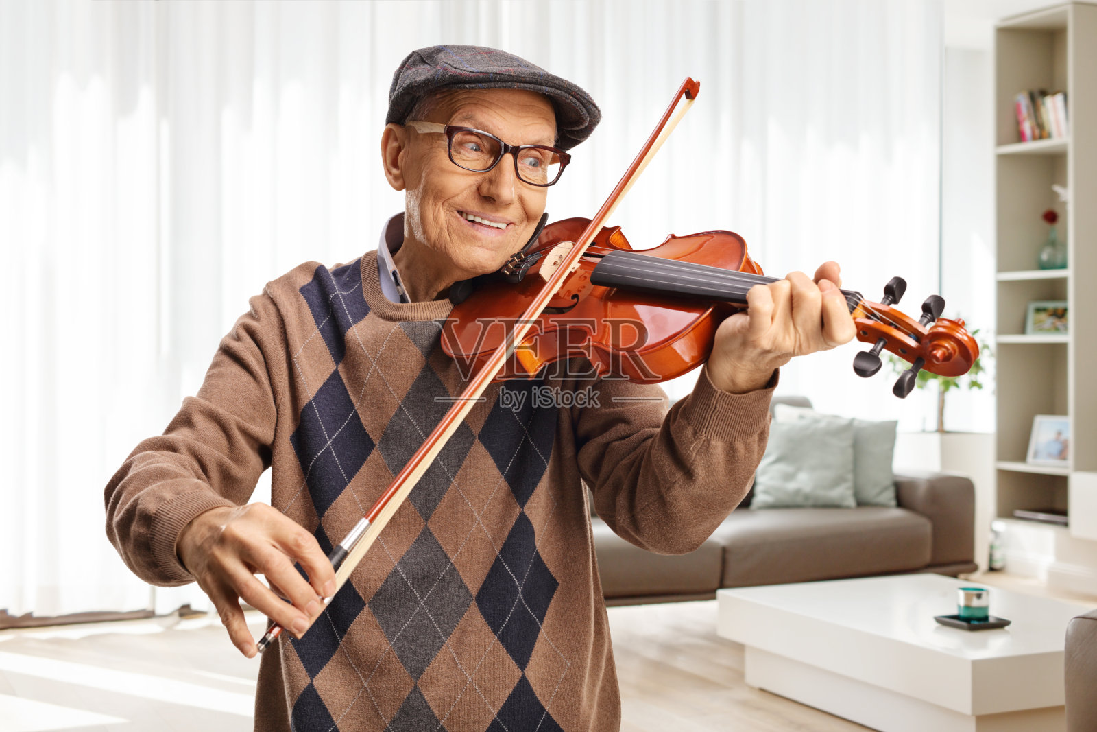 快乐的退休老人在家里拉小提琴照片摄影图片
