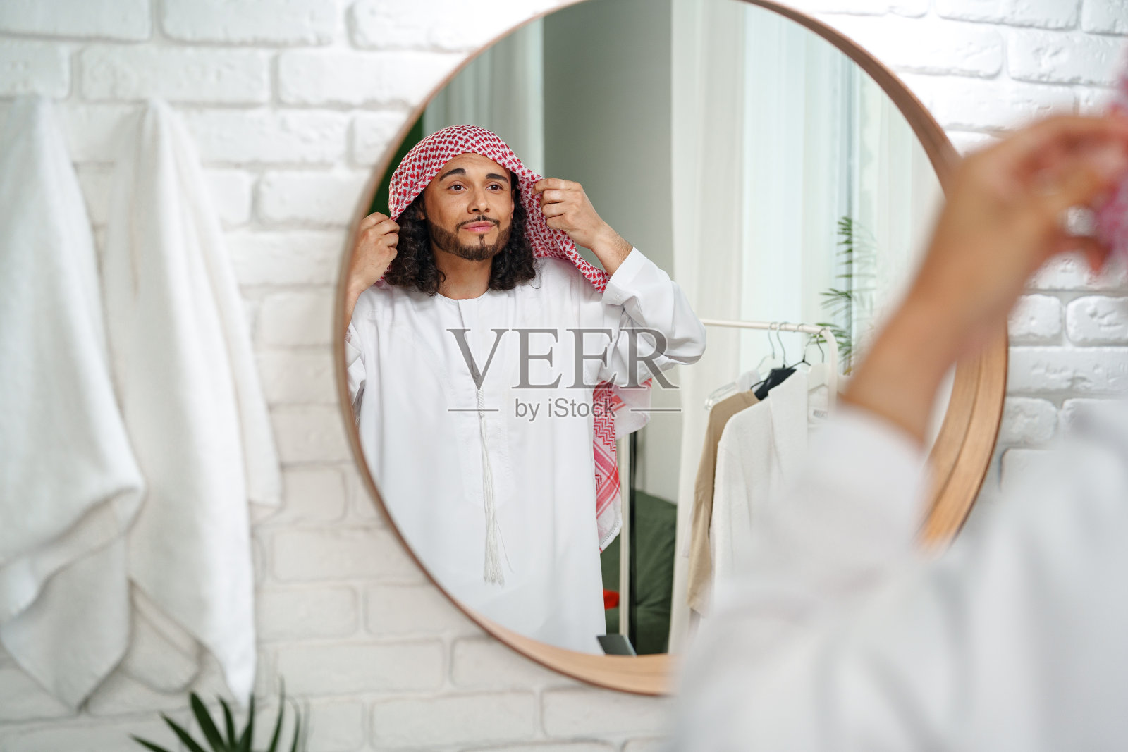 一个年轻的阿拉伯人正在梳妆，看着浴室里的镜子照片摄影图片