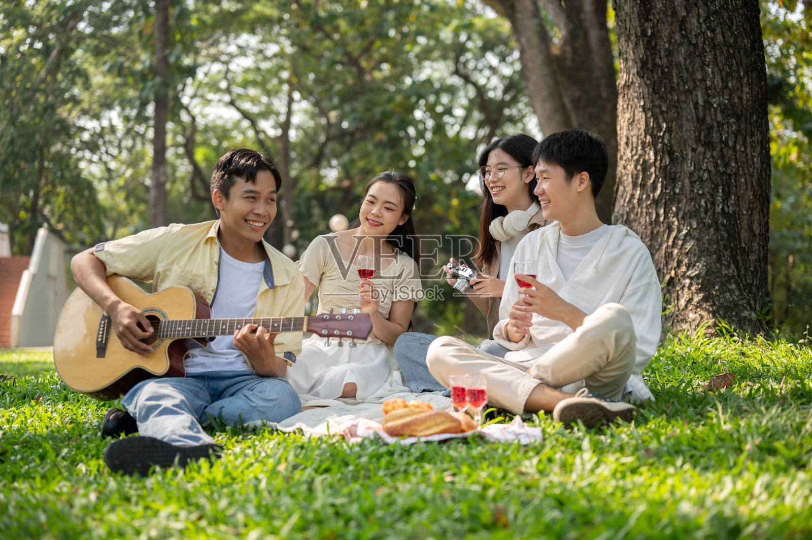 一群快乐的不同的年轻亚洲朋友正在一个美丽的公园里享受野餐。照片摄影图片