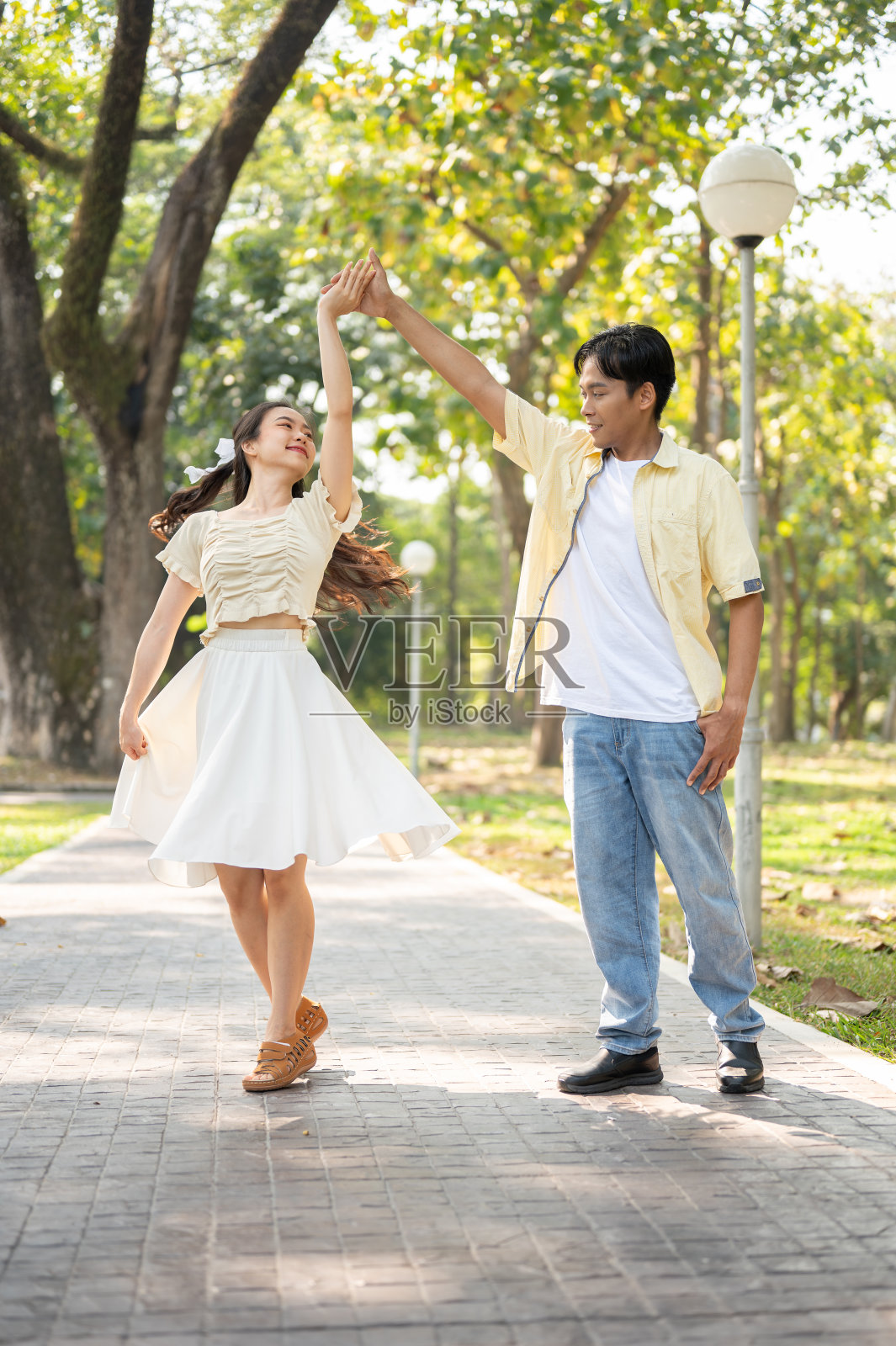 一对可爱的年轻亚洲夫妇在一个美丽的绿色公园里一起跳舞。调情,约会照片摄影图片