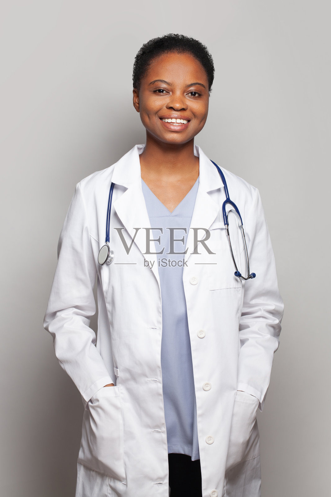 漂亮的女医生穿着医疗制服，灰色背景上有听诊器照片摄影图片