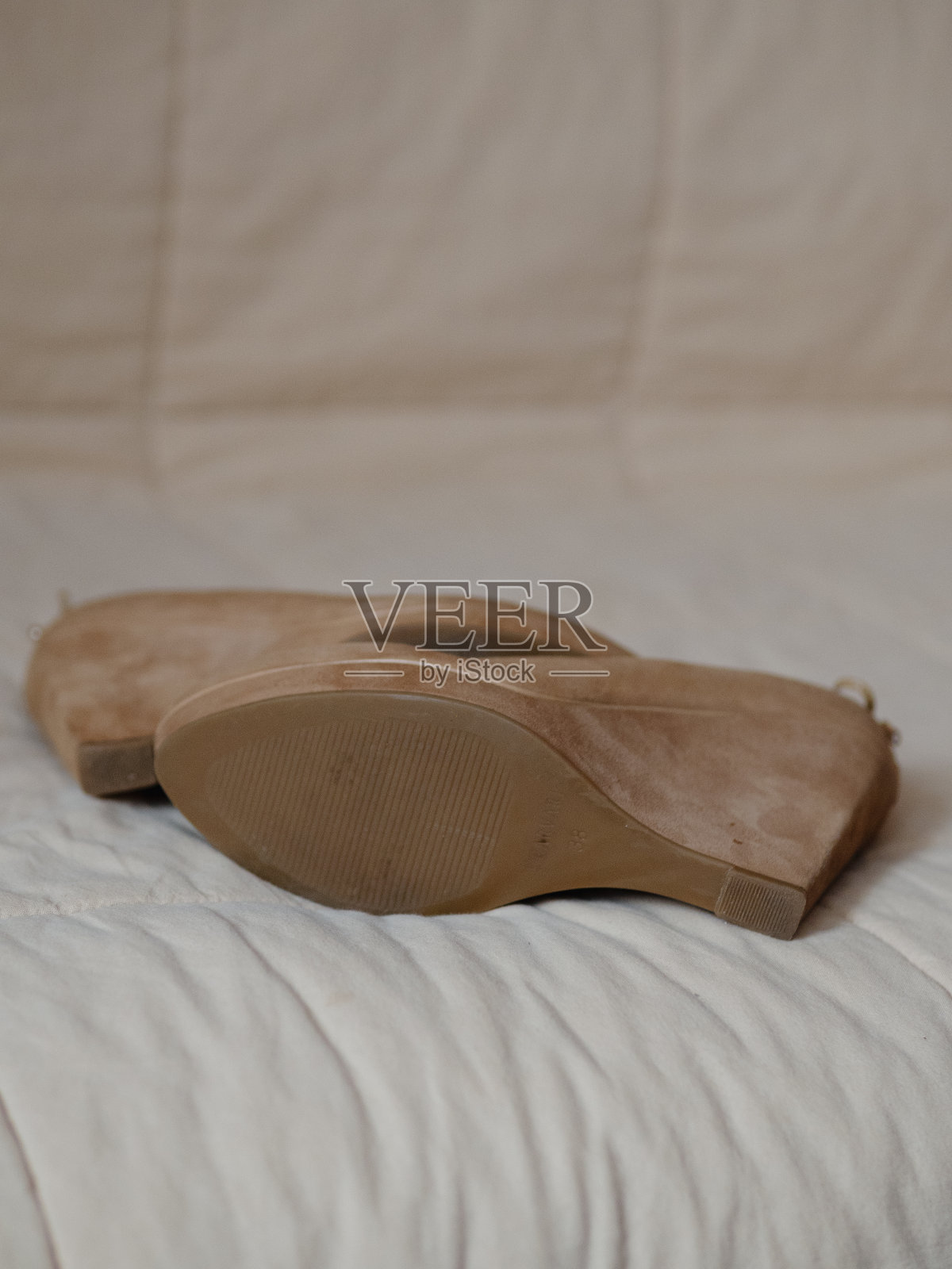 垂直直从上面近距离拍摄的妇女的米色高厚底鞋的真皮(麂皮)。背面装饰有鞋带蝴蝶结。罕见的比目鱼。照片摄影图片