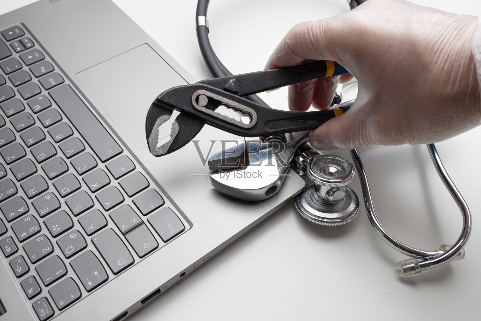 手提电脑上有扳手和听诊器的手，特写。的概念照片摄影图片